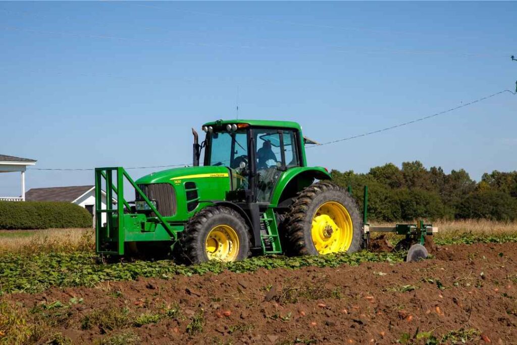 Green John Deere tractor working in a farm field – representing rural lifestyle and equipment relevant to Tractor Supply Sales Associate job duties in 2025.
