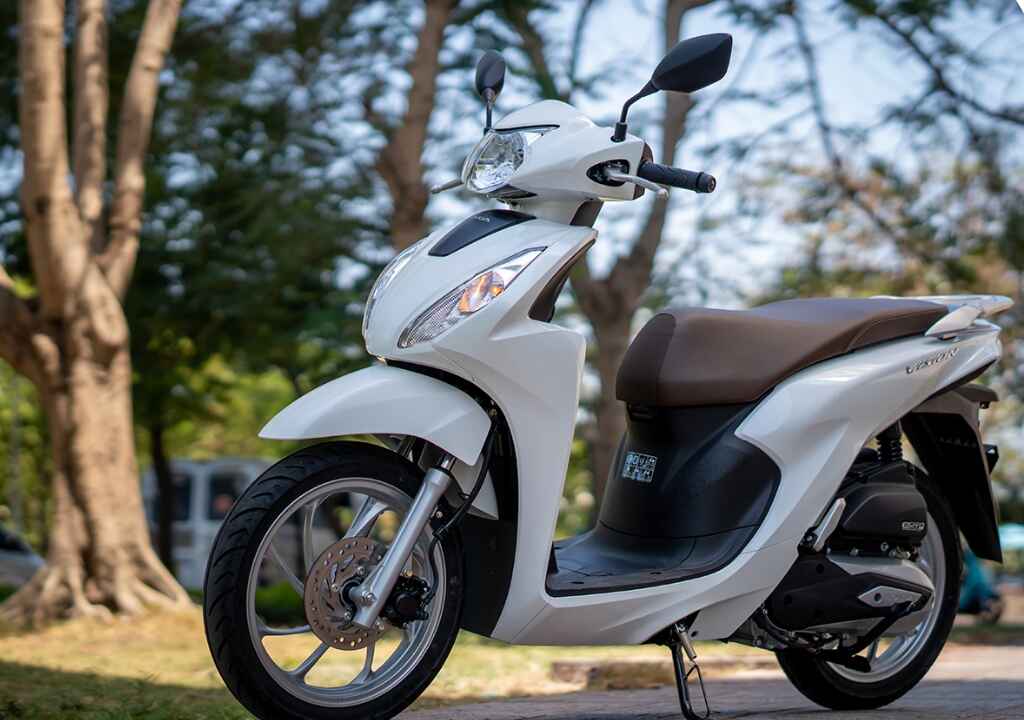 Xe máy Vision 2025 trắng parked outdoors showcasing sleek design, stylish white body, and modern features for 2025.