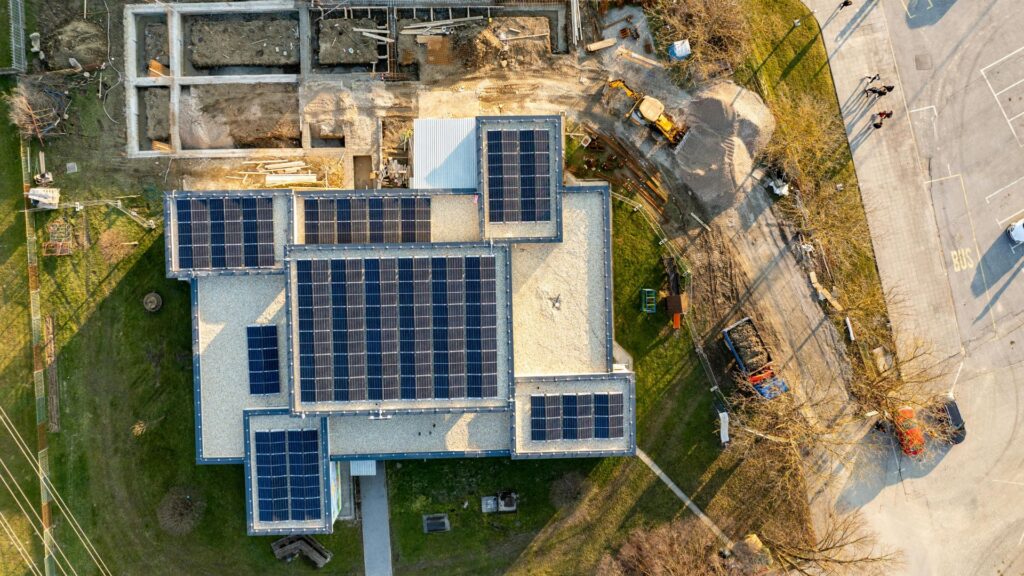 Aerial view of modern building with rooftop solar panels and 12 volt solar battery chargers installed for clean energy generation in the USA