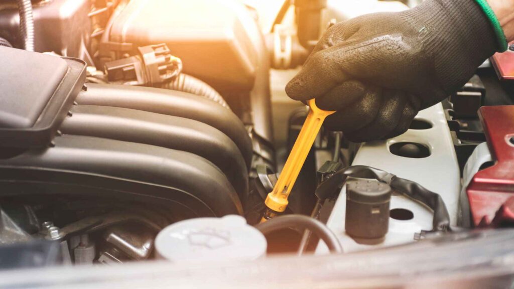 Mechanic checking engine oil level to explain whether Do Electric Cars Need Oil Changes