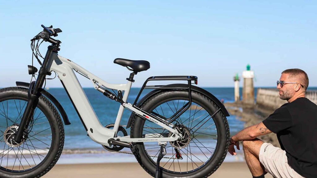 A man sitting by the beach with an electric bike, representing performance and reliability powered by the perfect electric bike charger.